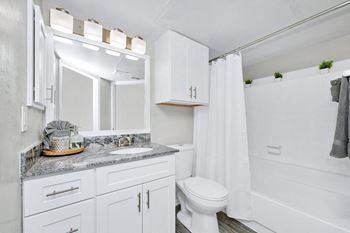 Bathroom with white cabinets and a toilet and a sink