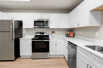 an empty kitchen with white cabinets and stainless steel appliances