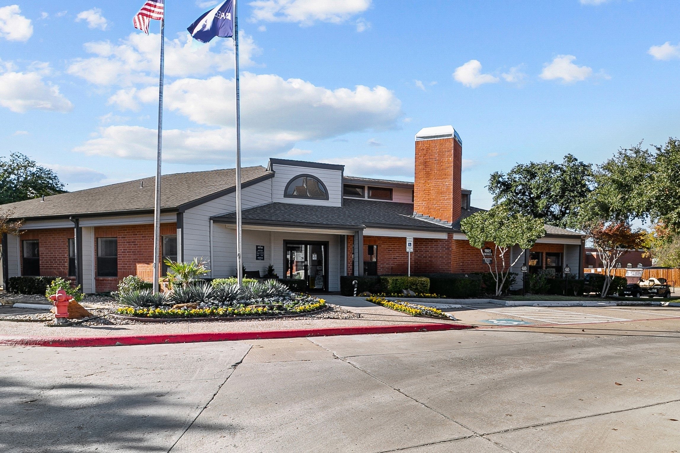 a brick building with two flags and a parking lot