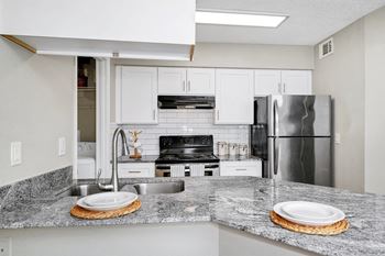 a kitchen with granite counter tops and a stainless steel refrigerator