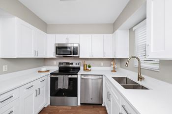 a white kitchen with stainless steel appliances and white cabinets