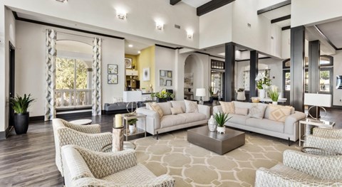 A spacious living room with white furniture and a patterned rug.
