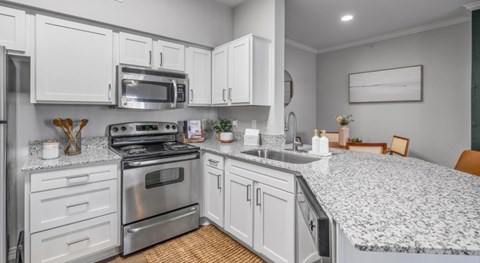 A kitchen with white cabinets and a stainless steel refrigerator.