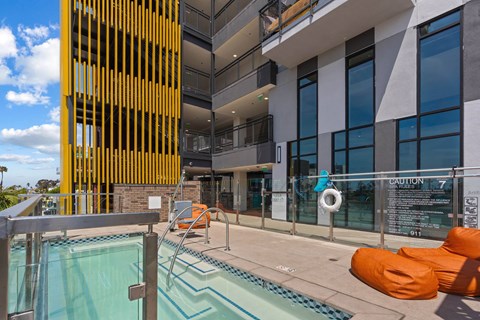 Rooftop pool area with spa and orange lounge seating at AMP 30 Apartments, San Diego, 92116