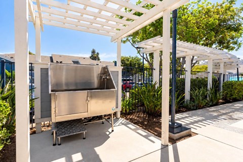 A large metal container is under a white pergola.