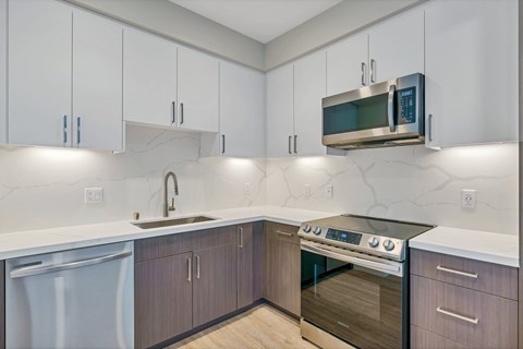 A modern kitchen with a stainless steel oven and white cabinets.