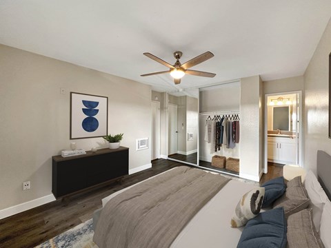 A bedroom with a bed, a ceiling fan, and a mirror.
