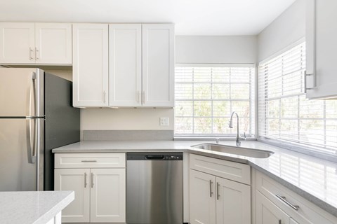 A kitchen with white cabinets and a black refrigerator.