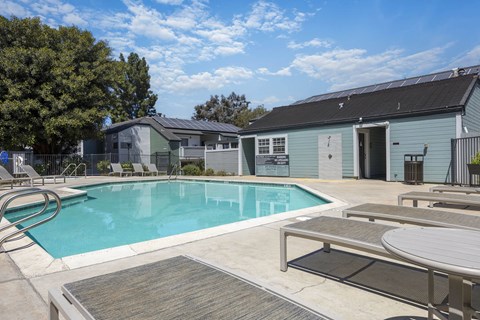 A swimming pool with a deck and a building in the background.