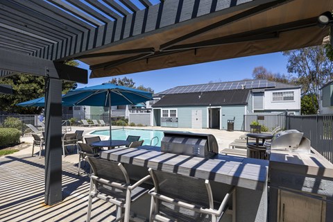 A patio with a striped sunshade and a pool table.