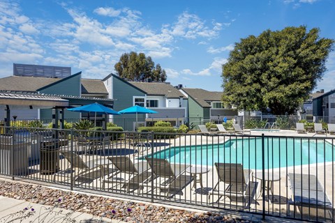 A pool surrounded by chairs and a fence.