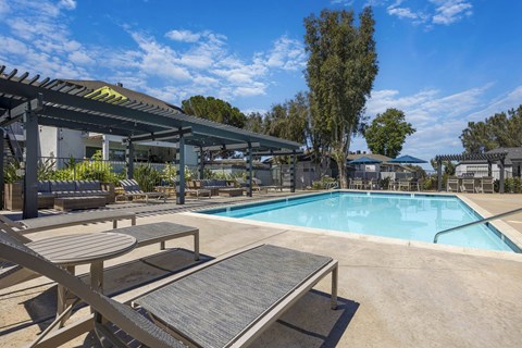 A pool area with sun loungers and a shaded area.