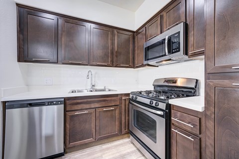 A kitchen with dark wood cabinets and stainless steel appliances.