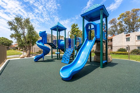 A playground with a blue slide and a blue tower.