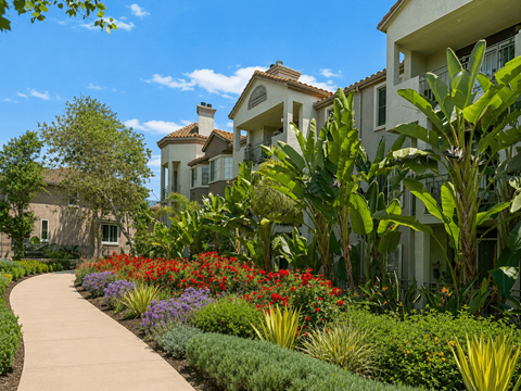 A garden with a variety of plants and flowers in front of a building.