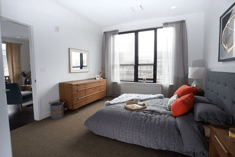 Spacious bedroom with gray upholstered bed at 22 & 28 Mechanic Street Apartments, Quincy, Massachusetts