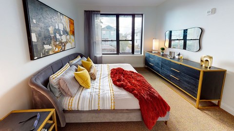 A bedroom with a bed, nightstand, and a painting on the wall.