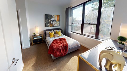 A bedroom with a bed, a nightstand, a chair, and a painting on the wall.