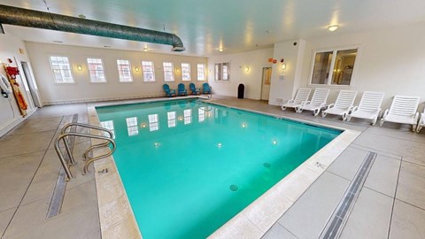 Indoor pool with lounge chairs and windows at Bostonian Shoe Lofts Apartments, Whitman, MA 02382