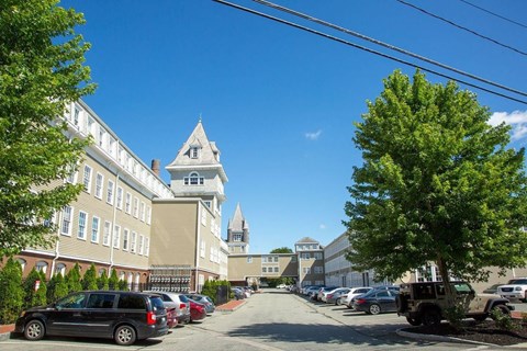 Historic building exterior with parking and tower features at Bostonian Shoe Lofts Apartments, Whitman, MA 02382