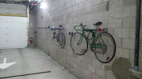 Two bikes are parked on a wall in a garage.