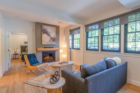A living room with a fireplace, a blue couch, and a painting on the wall.