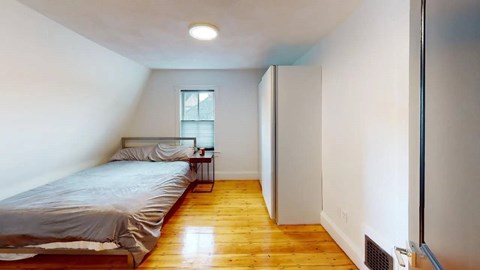 Minimalist bedroom with wood floors and sloped ceiling at 154 Granite Apartments, Quincy, MA