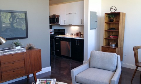 A grey chair is in the foreground of a kitchen.