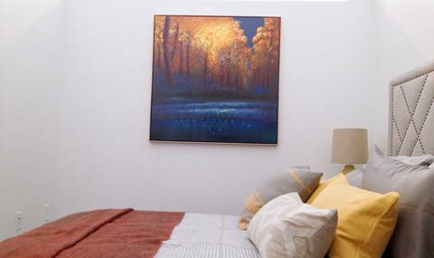Bedroom with autumn landscape painting and accent pillows at 68 Beale Apartments, Quincy, MA