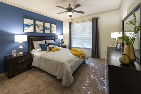 A bedroom with a bed, nightstands, and a ceiling fan.