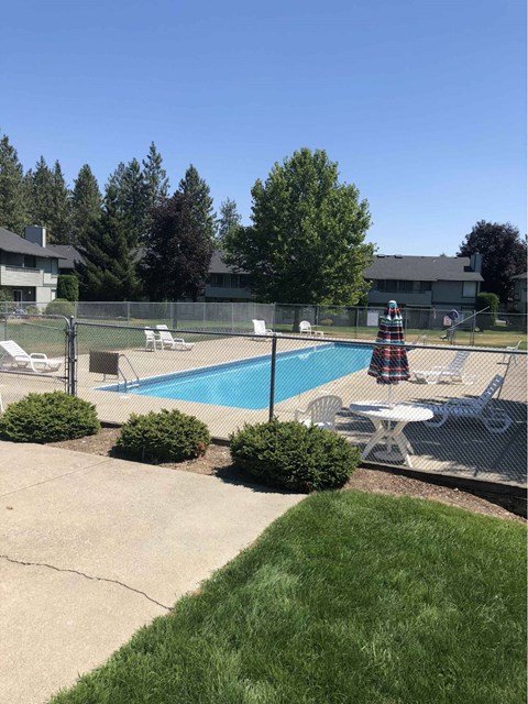 A pool surrounded by a fence and chairs.
