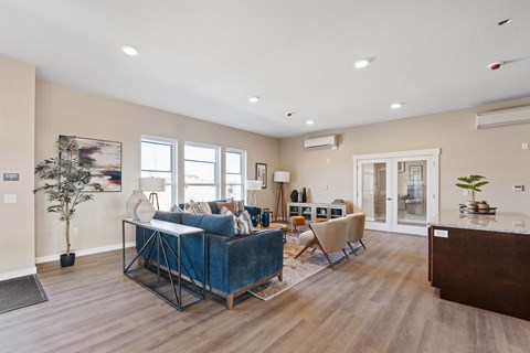 A living room with a blue couch and a wooden floor.
