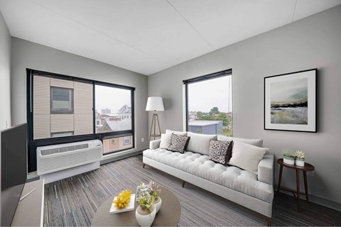 A modern living room with a white sofa and a large window.