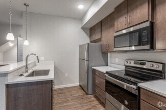 A modern kitchen with dark wood cabinets and stainless steel appliances.
