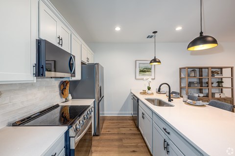 A modern kitchen with a black refrigerator and a white countertop.