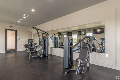 A spacious gym with a variety of equipment including a treadmill, a stationary bike, and a rowing machine.