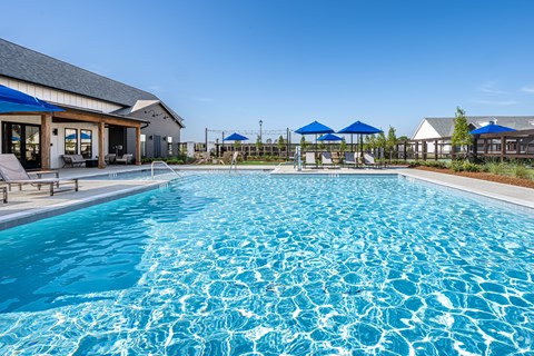 A large swimming pool with blue umbrellas and chairs.