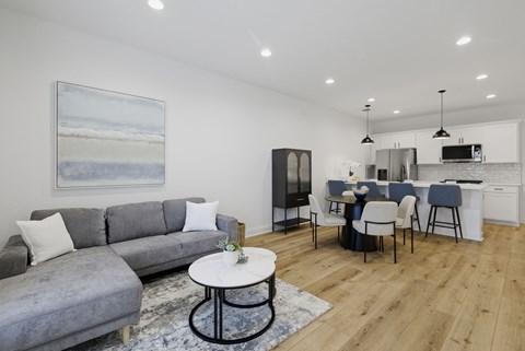 A modern living room with a grey sofa and a painting of a beach scene on the wall.