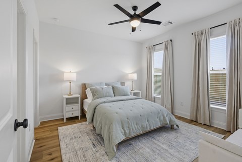 A bedroom with a bed, nightstands, and a ceiling fan.
