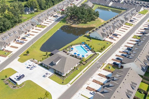 A bird's eye view of a residential area with houses, a swimming pool, and a lake.