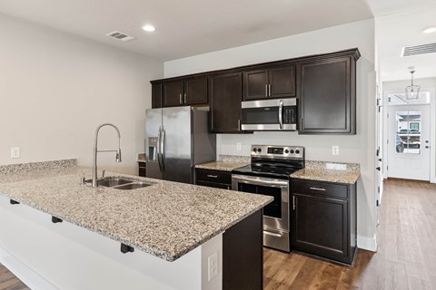 A kitchen with granite countertops and black cabinets.