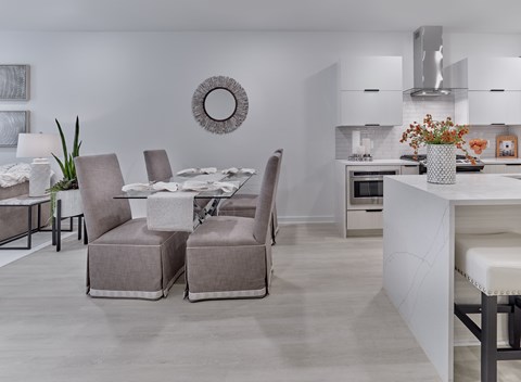 A modern dining room with a white table and grey chairs.