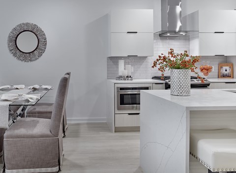A modern kitchen with a grey chair and a white island.