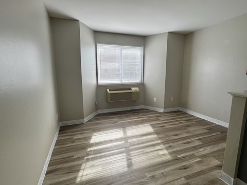 A room with wooden flooring and a window with blinds.