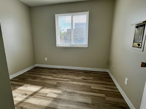 A room with wooden flooring and a window with blinds.