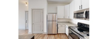 A kitchen with a stove, microwave, refrigerator, and oven.