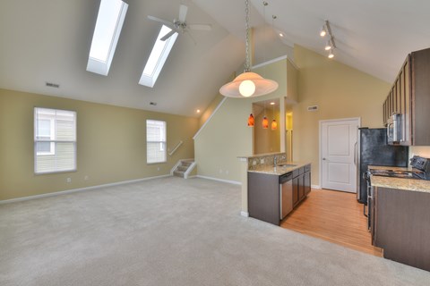 A spacious kitchen and living room with a skylight and a hanging light fixture.