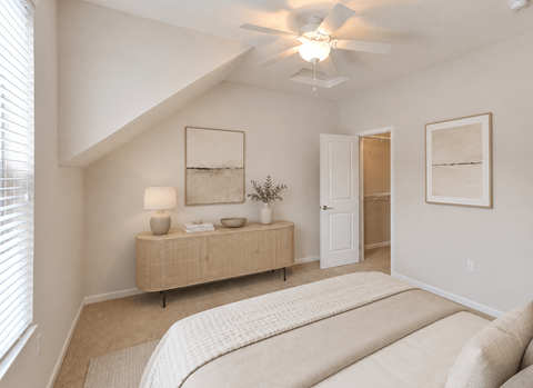 A bedroom with a bed, a dresser, and a ceiling fan.