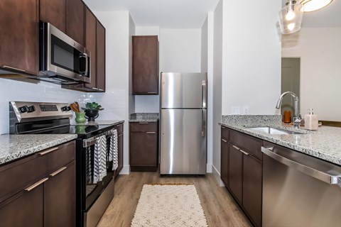 A kitchen with a refrigerator, microwave, and oven.