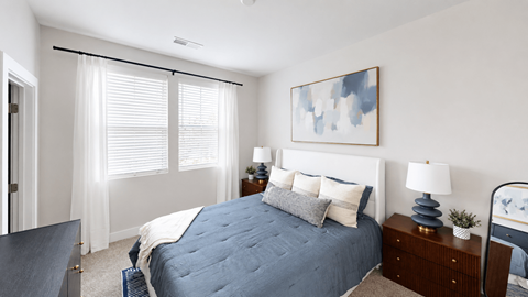 A bedroom with a large bed, a nightstand with a lamp, and a painting on the wall.